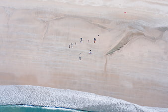 Aerial View of People Walking on Sandy Beach with Ocean Waves