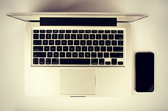 Top view of silver laptop and smartphone on white desk