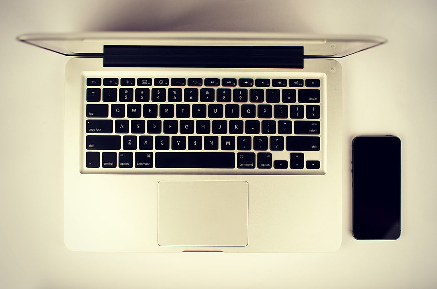 Top view of silver laptop and smartphone on white desk