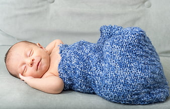 Sleeping newborn baby wrapped in blue knitted blanket