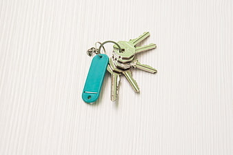 Set of house keys with teal tag on white wood