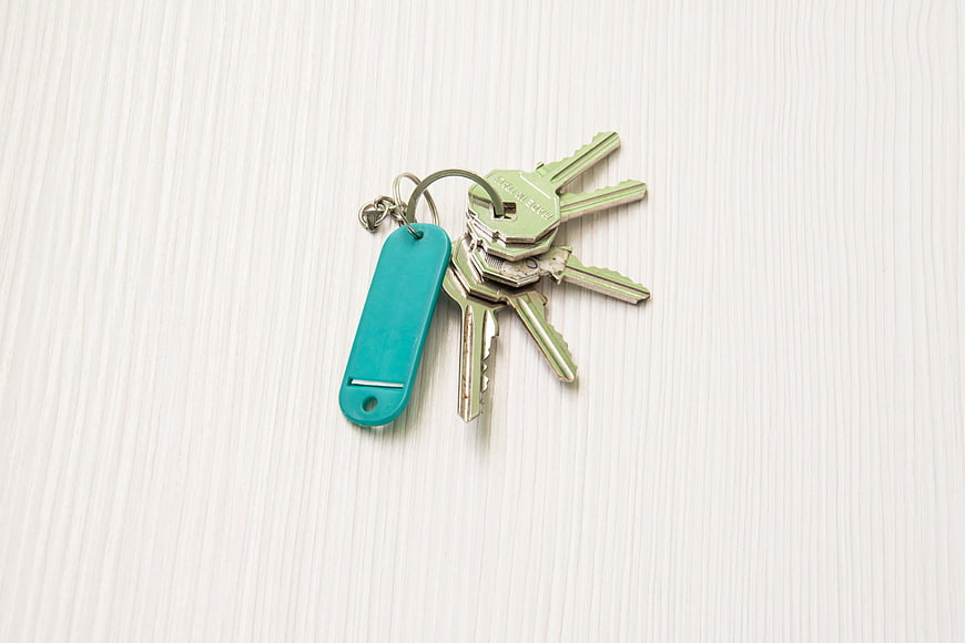 Set of house keys with teal tag on white wood