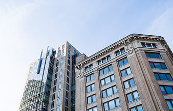 Low angle view of modern and classical office buildings against blue sky