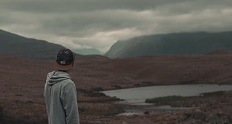 Man in Hoodie Looking at Misty Mountain Landscape