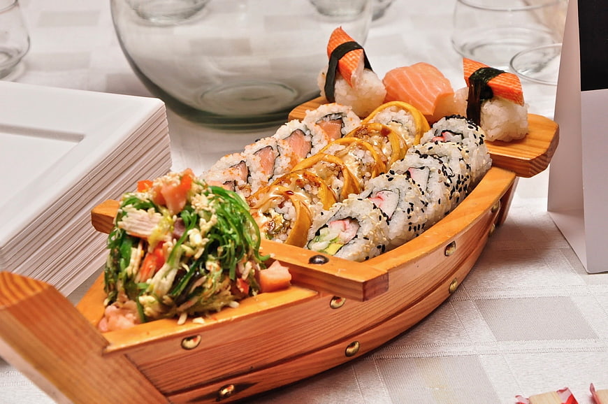 Sushi Platter Served in Wooden Boat on White Tablecloth