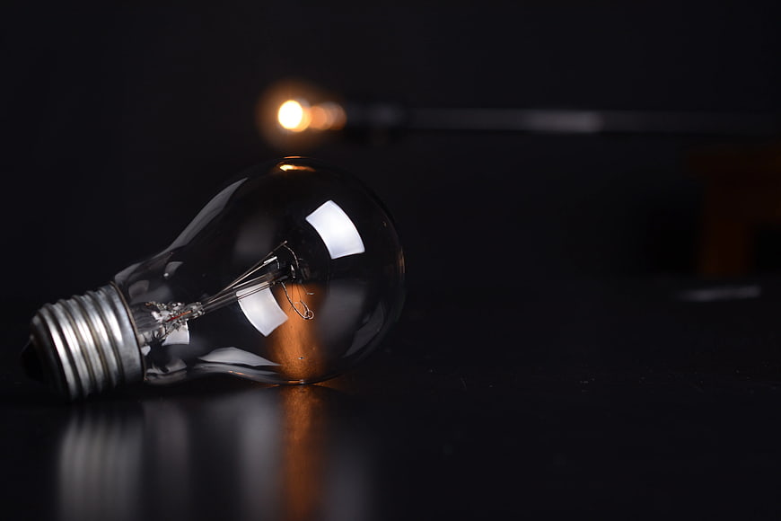 Clear Filament Light Bulb on Dark Surface with Bokeh