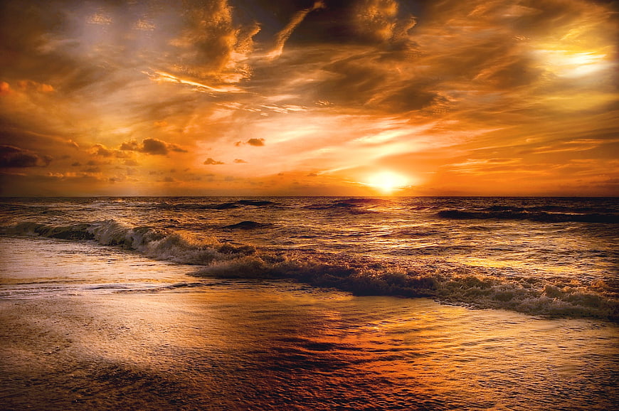 Dramatic Golden Sunset Over Ocean Waves And Cloudy Sky