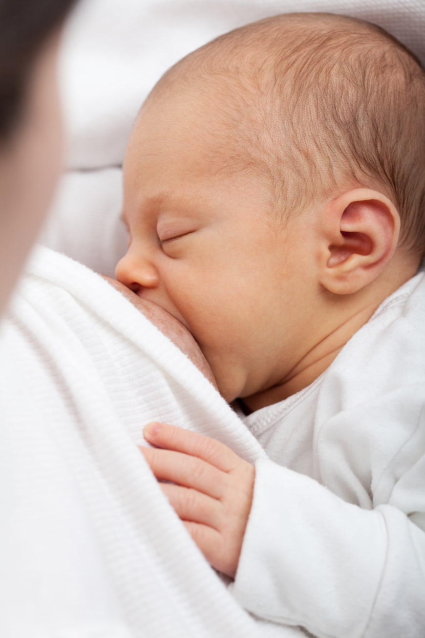 Close-up of newborn baby breastfeeding peacefully