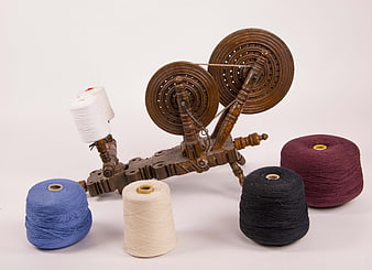 Vintage wooden spinning wheel with colorful yarn spools