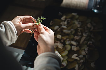 Hands Stripping Rosemary Sprig Over Chopped Vegetables