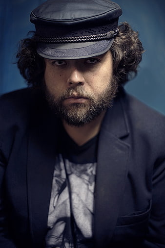 Portrait of a bearded man wearing a dark flat cap and jacket