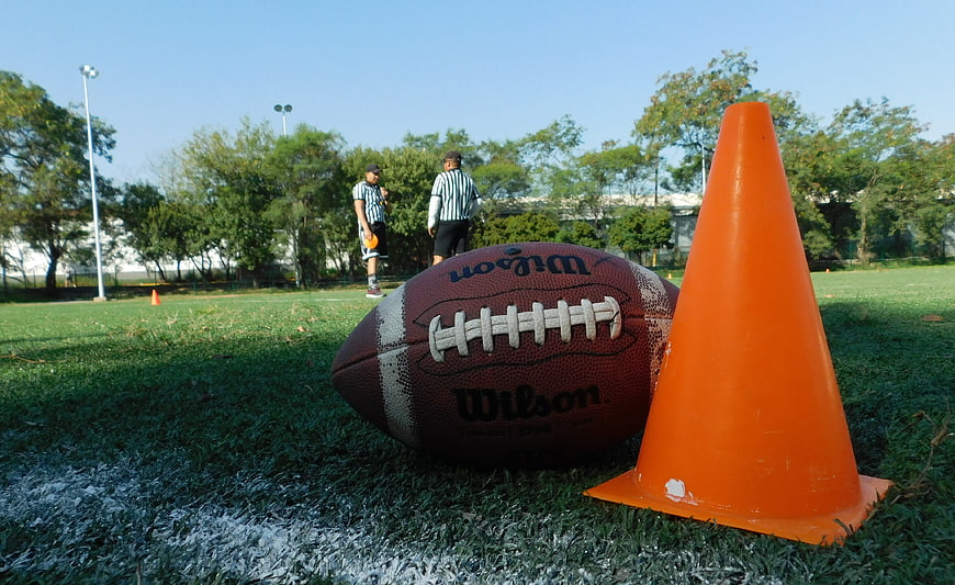 American football and orange cone on grass field