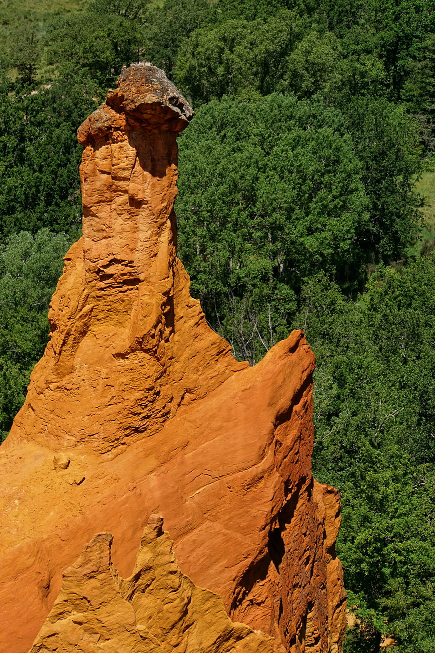 Red sandstone rock formation in green forest landscape