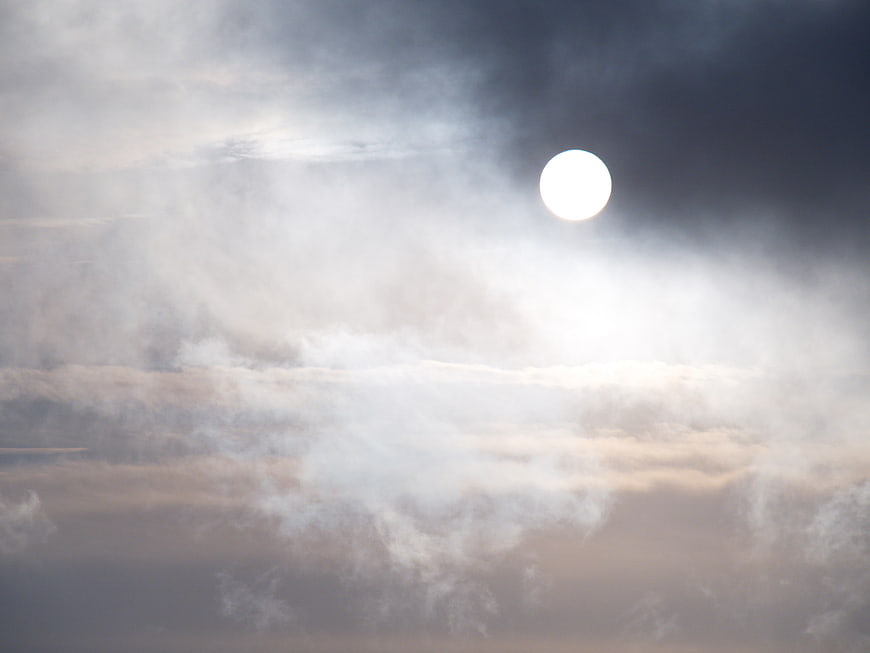 Bright Sun Shining Through Dramatic Clouds in Moody Sky