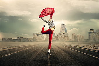 Woman dancing on road with red scarf against city skyline
