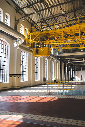 Spacious industrial interior with yellow crane and sunlight