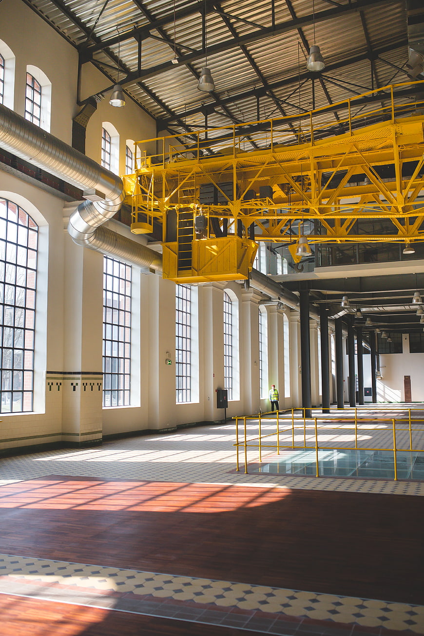 Spacious industrial interior with yellow crane and sunlight