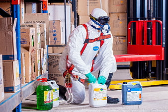 Worker in Hazmat Suit Handling Chemicals in Warehouse