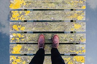 Top-down view of brown leather shoes on weathered wooden dock
