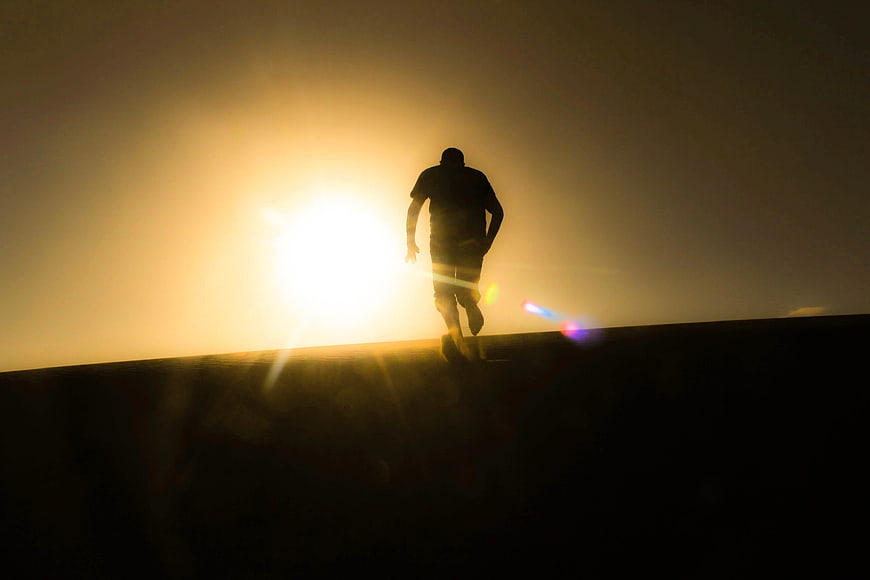 Silhouette of Man Running Uphill at Sunset