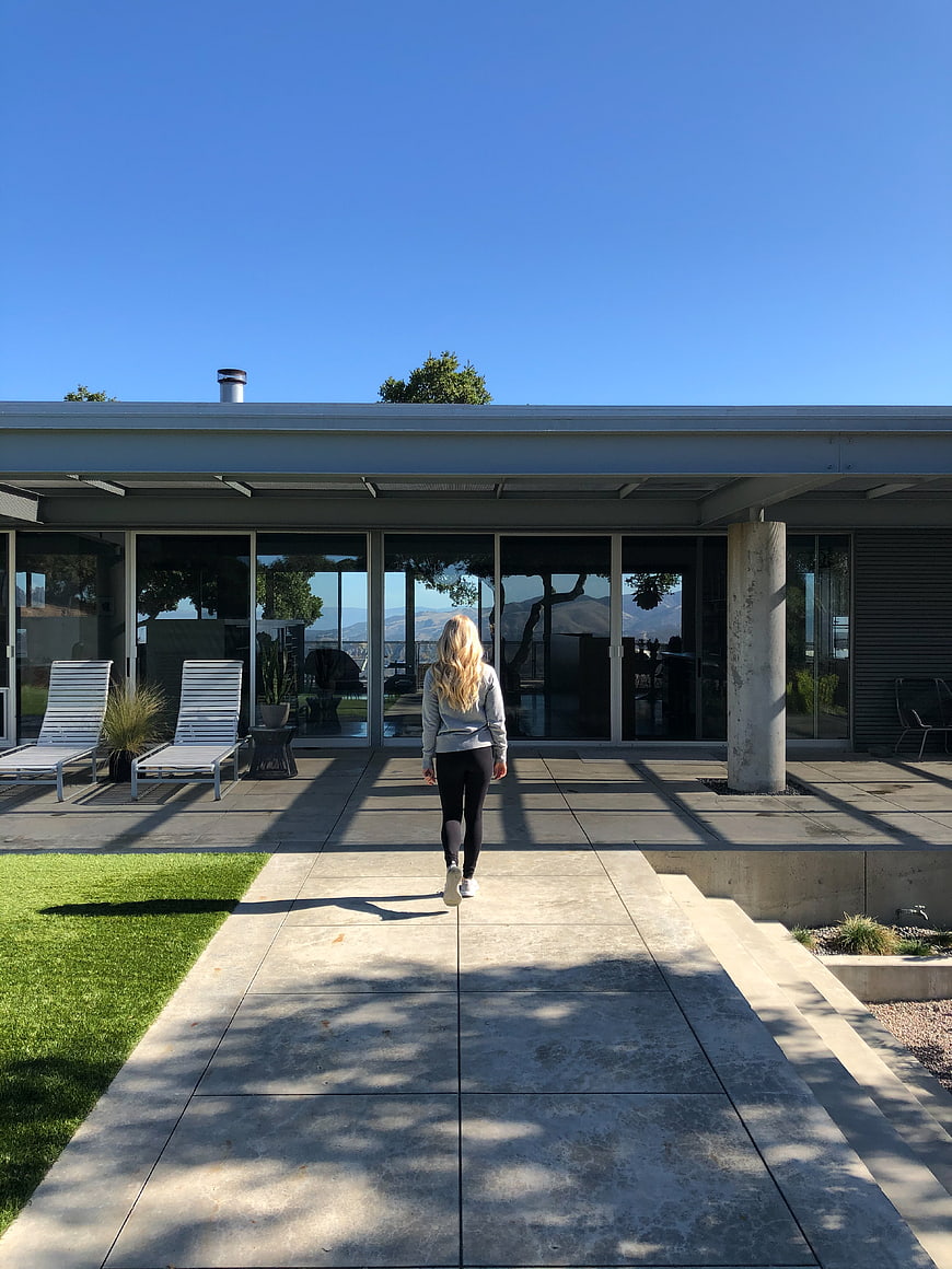 Woman walking toward modern mid-century home patio