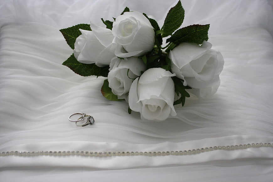 White Rose Bouquet and Wedding Rings on White Fabric