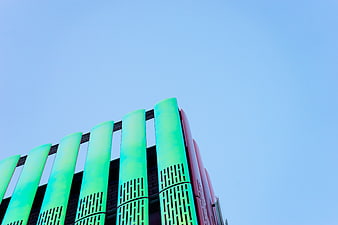 Modern Green and Red Architectural Columns Against Blue Sky