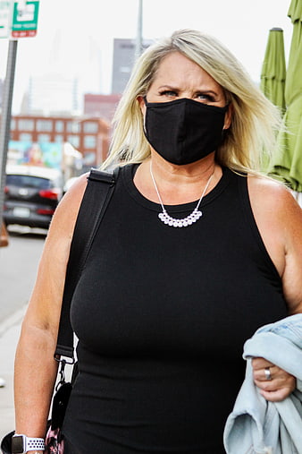 Blonde woman wearing black face mask on city street
