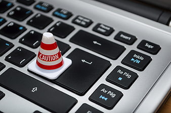 Miniature Caution Traffic Cone On Laptop Keyboard Key