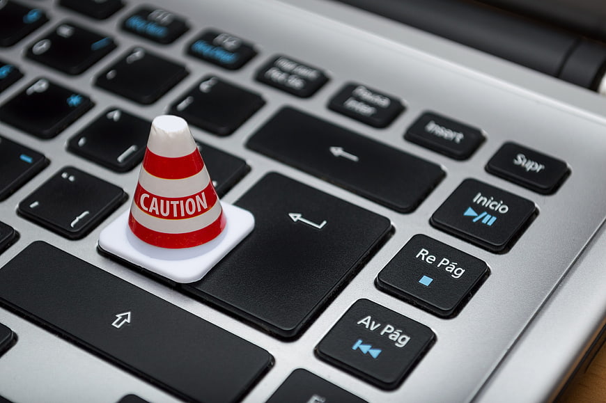 Miniature Caution Traffic Cone On Laptop Keyboard Key