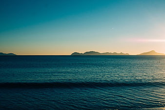 Serene Ocean Sunset with Distant Island Silhouettes