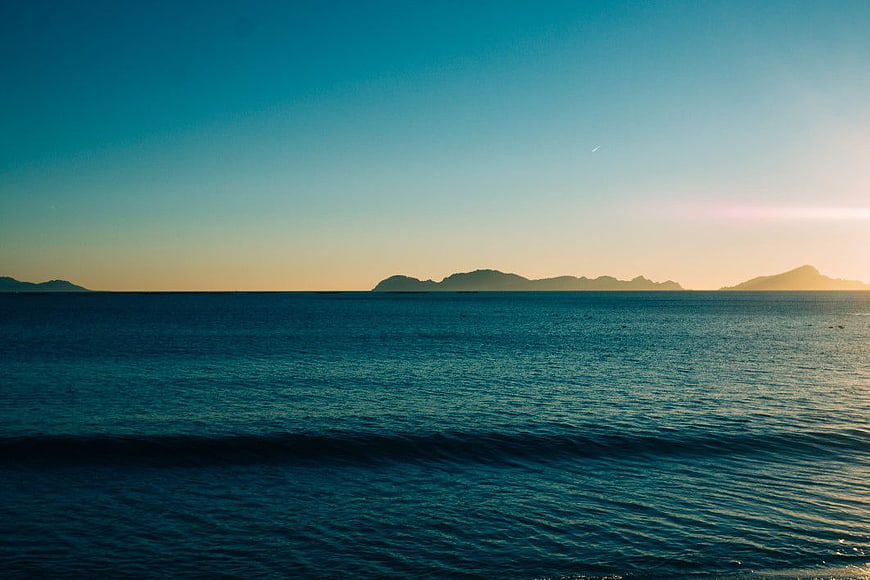 Serene Ocean Sunset with Distant Island Silhouettes