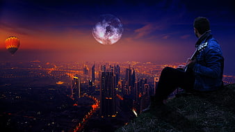 Man playing guitar on hill overlooking city at night with moon