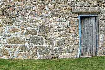 Rustic weathered wooden door set into a textured old stone wall