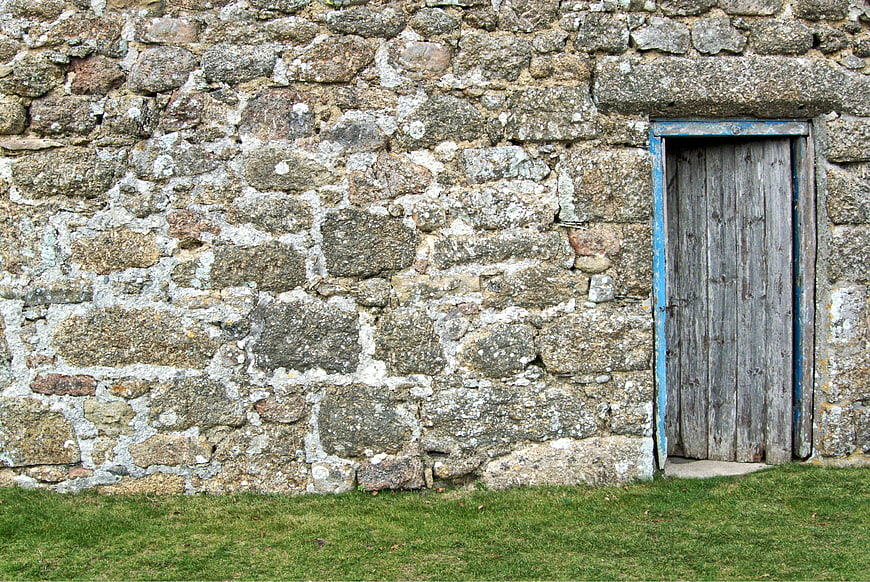 Rustic weathered wooden door set into a textured old stone wall