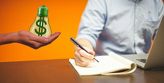 Hand holding light bulb with dollar sign over business meeting
