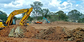 Heavy Excavators Working on Construction Site with Dirt Piles