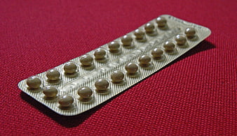 Blister pack of contraceptive pills on red textured fabric background