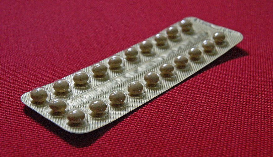 Blister pack of contraceptive pills on red textured fabric background