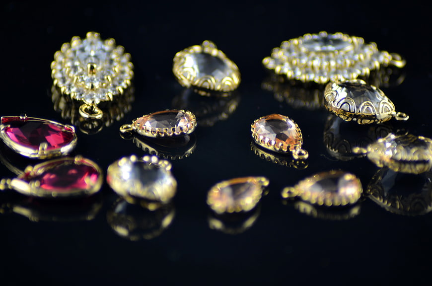 Gold Crystal Jewelry Pendants On Black Reflective Surface