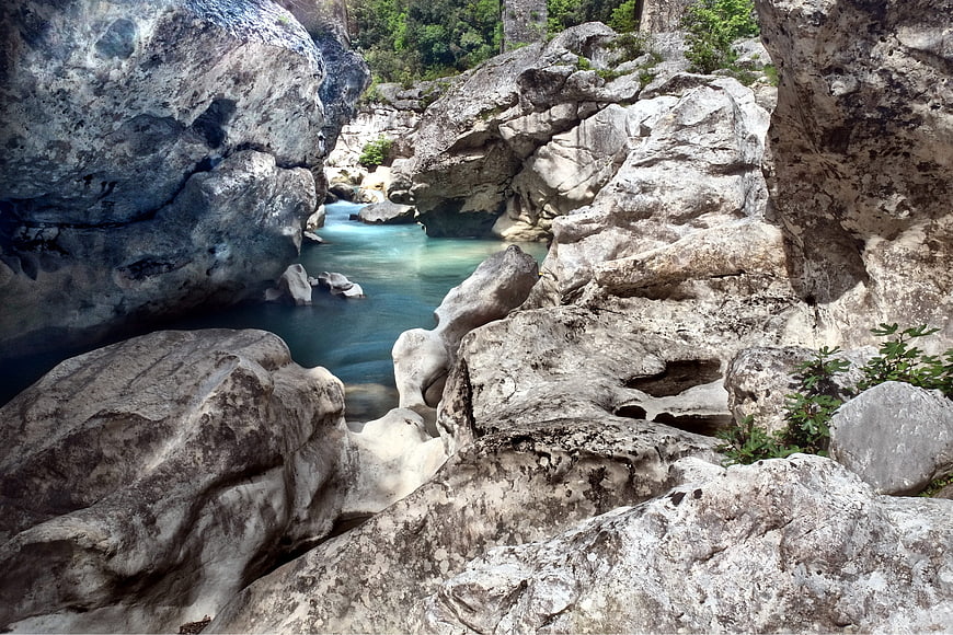 Rocky River Canyon With Turquoise Water And Lush Vegetation