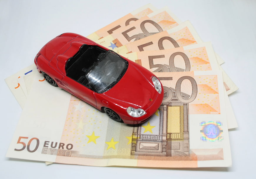 Red toy car on pile of fifty euro banknotes