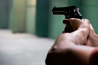 Close-up of hands aiming a black pistol at a target