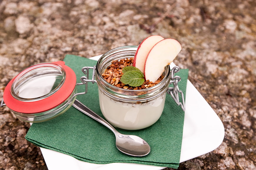Healthy yogurt parfait with granola and apple slices in glass jar