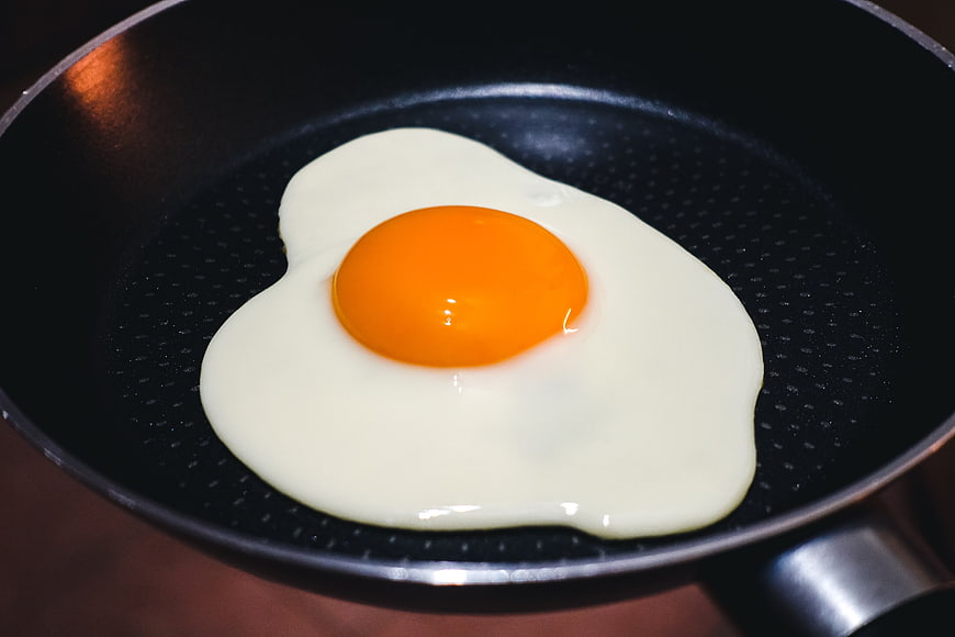 Sunny side up egg frying in black pan