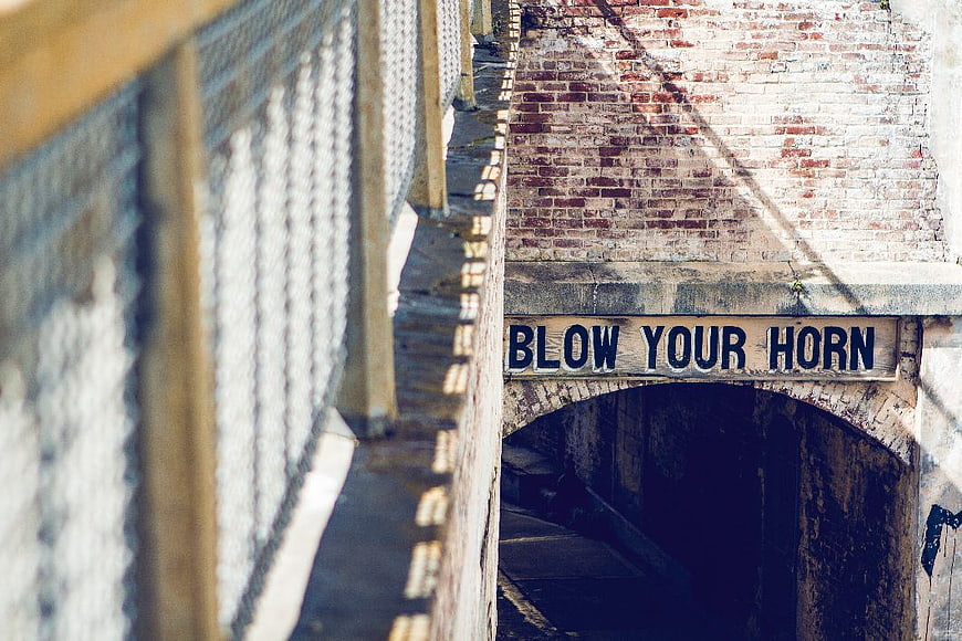 Vintage Blow Your Horn Sign on Brick Tunnel Arch