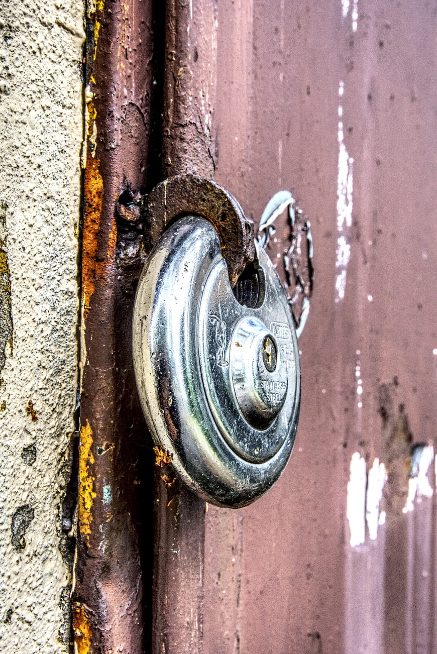 Close-up of rusty padlock on weathered metal gate