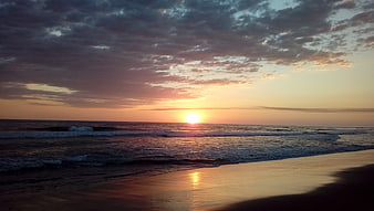 Serene sunset over ocean waves with dramatic clouds