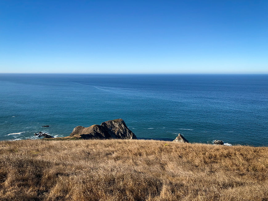 Scenic Coastal Cliff View with Dry Grass and Blue Ocean