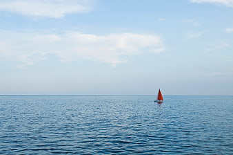 Lone Orange Sailboat on Calm Blue Ocean